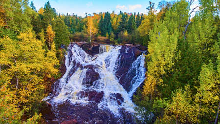 Trip Aerial of fall forest surrounding the Eagle River Falls steep cliff waterfallの写真素材
