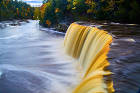 Tahquamenon Falls with golden brown waterfall and swirling river during fallの写真素材