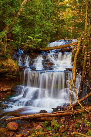Scenic waterfalls cascading down multiple tiers in the fall forestの写真素材