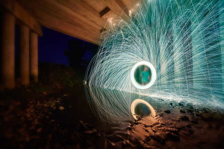 Man with green shirt creates portal of white light and shower of white and green sparks from steel...