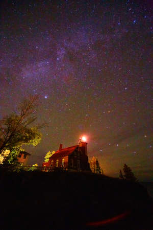 Milky Way over harbor lighthouse with light onの写真素材
