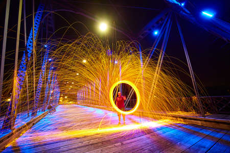 Ghostly man in middle of a ring of yellow sparks at night on a bridgeの写真素材