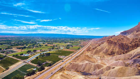 Rough tan mountains next to highway and Palisade town for peach farmsの写真素材