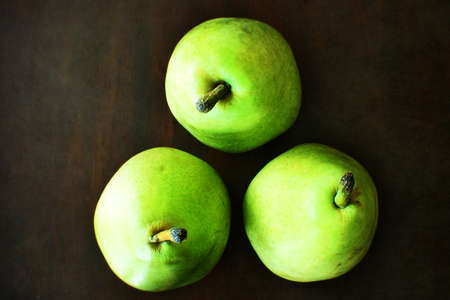 Three bright green pears arranged in a triangle from above for a still lifeの写真素材