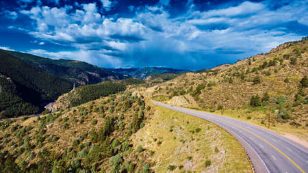 Open road through the rocky mountains with storm cloudsの写真素材