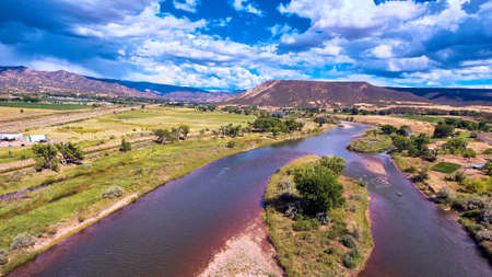 Split river through lush forest by desert mountainsの写真素材
