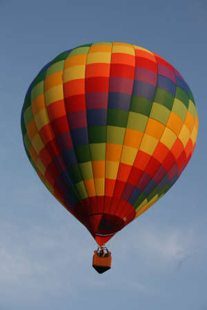 A hot air balloon with rainbow squares pattern flying in a cloudy skyの写真素材