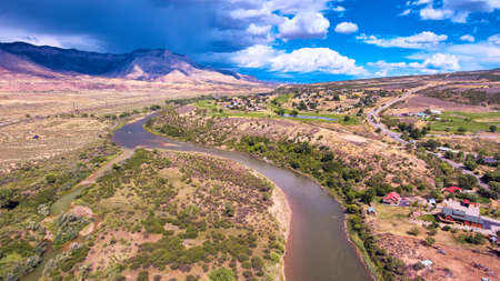 River cutting through the desert with mountains and stormの写真素材