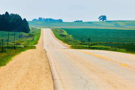 Sideview of road leading down to lush green fieldsの写真素材