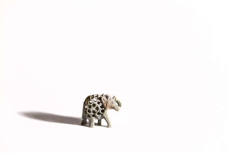 Tiny stone elephant casts a long shadow on the white backgroundの写真素材