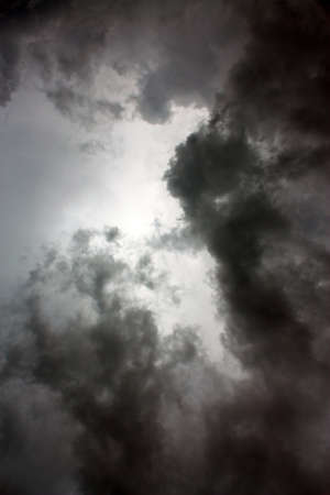 Ominous dark clouds almost blot out the sun which silhouettes them