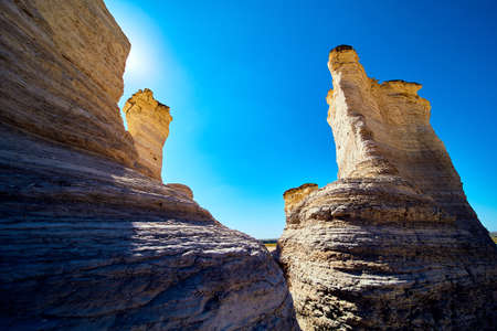 Pillars of white and gold rock blocking sun in desert against blue skyの写真素材