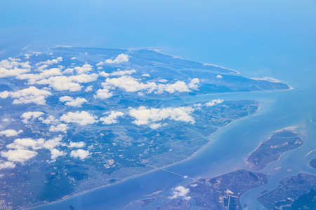 Airplane view of land with clouds coveringの写真素材