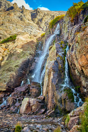 Close up of large waterfall over mossy rocks in mountains
