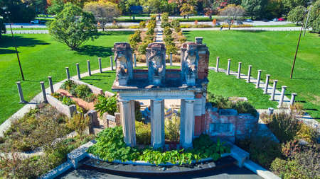 Old ruins in park with three stone columns and large statues