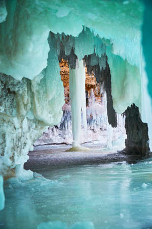 Tunnel of green and blue ice in cave leading to large icicleの写真素材