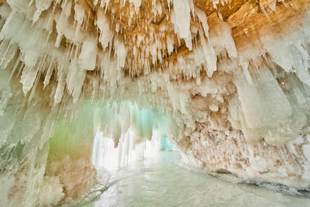 Ice cavern on frozen lake with ceiling covered in small iciclesの写真素材