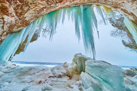 Large chunks of broken icicles at entrance to ice cave with hanging blue iciclesの写真素材
