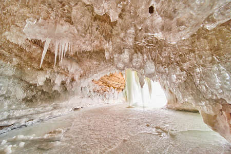 Beautiful pure and clear icicles covering ceiling of ice cave on lakeの写真素材