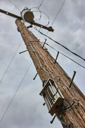 Telephone pole looking up detail on cloudy day for communication and powerの写真素材
