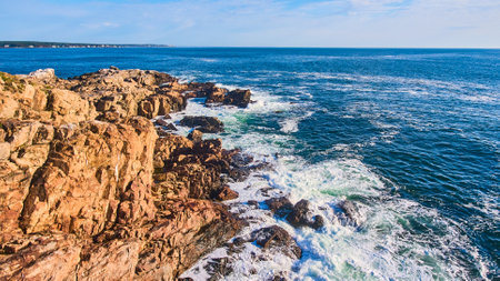 Cliffs of ocean in Maine with waves crashing over bouldersの写真素材