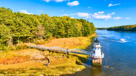 Aerial of small lighthouse Doubling Point on Maine Coast with fall foliage and warm lightの写真素材