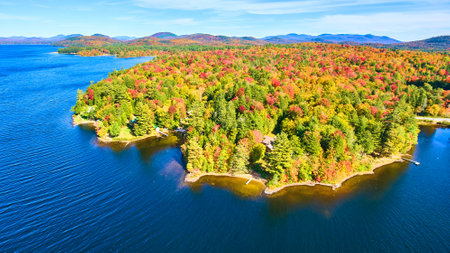 Blue water lake aerial focused on coastline filled with fall forests and mountainsの写真素材