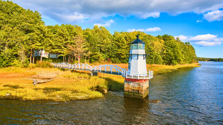 Fall foliage on coast with small lighthouse in Maine and walkwayの写真素材
