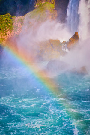 Rainbow crossing through Niagara River with American Falls behind in detailの写真素材