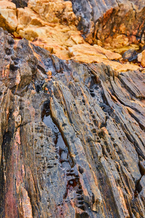 Endless layers of rocks on coast with holes and divots and slots filled with water