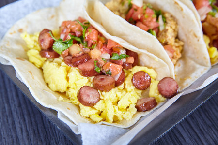 Mexican breakfast three tacos sausage chorizo bacon egg tomato chives flour tortillasの写真素材