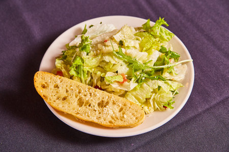 Small side lunch salad with ciabatta white bread slice plain iceberg lettuce parmesan cheese tomatoの写真素材