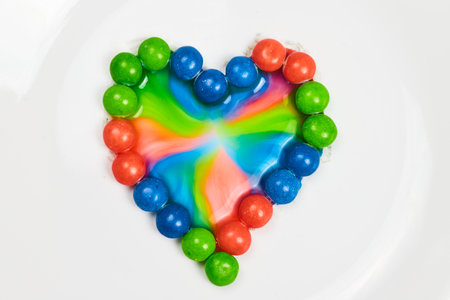 Water colored by tie dye effect from blue and green and pink skittle heart backgroundの写真素材