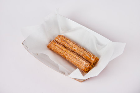 Two Mexican sweet churro pastries in whit tray on white backgroundの写真素材