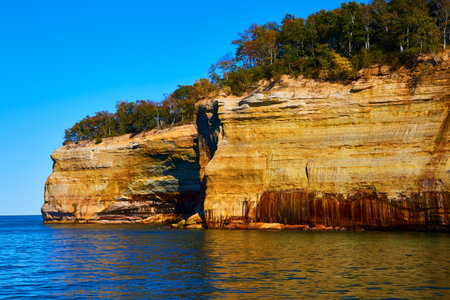 Cliff wall of pictured rocks at Michigan National Park with forest atop large cliffsの写真素材
