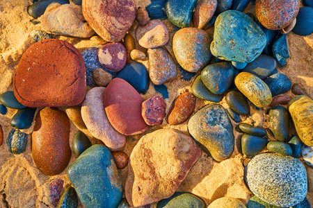 Multiple colors of smooth stones washed up on sandy shoreの写真素材