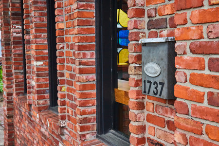 Old red brick building with protruding area around three windows and metal mailbox 1737