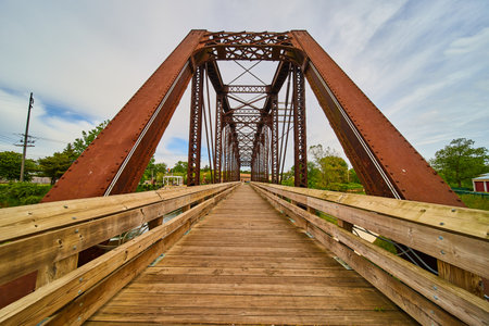 Wooden walking bridge cutting through rusty iron train bridge in Mount Vernon Ohioの写真素材