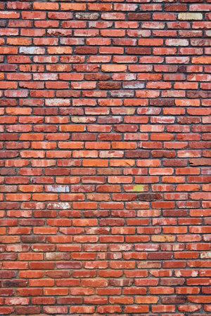 Massive and tall red wall with crumbling and faded bricks and blackening mortar background assetの写真素材