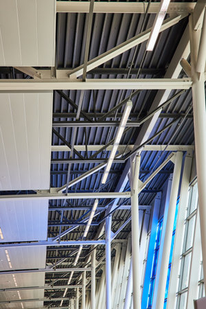 Blue glow from window art on abstract ceiling view with beams and polesの写真素材