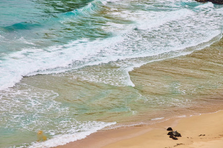 Waves crashing against sandy shore with exposed sandy beach on bottom right cornerの写真素材