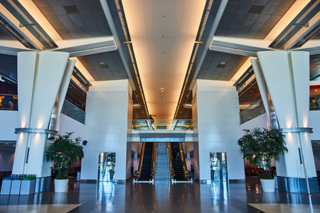 Symmetry inside generic airport with escalators framing in stairs and person on bridge walkwayの写真素材