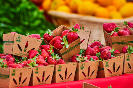 Ripe red strawberries in cardboard containers with colorful background at marketの写真素材