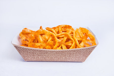 Side view of chicharrones de harina in textured tan serving boat on white background