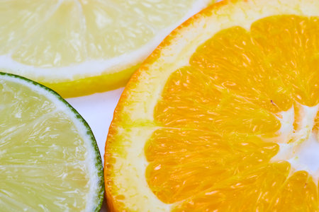 Close up or an orange slice with a lime and lemon on a white backgroundの写真素材