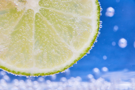 Green lime slice with silvery bubbles and blue backgroundの写真素材