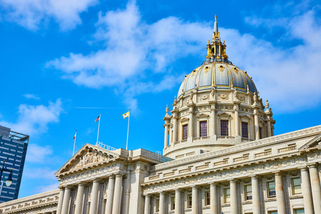 City hall with flags on top of pointed roof and blue and gold dome under gorgeous summer skyの写真素材