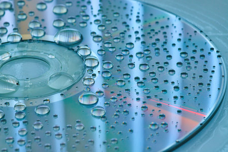 Calm blue and silver surface with silvery water droplets on CD surface and slate blue backgroundの写真素材