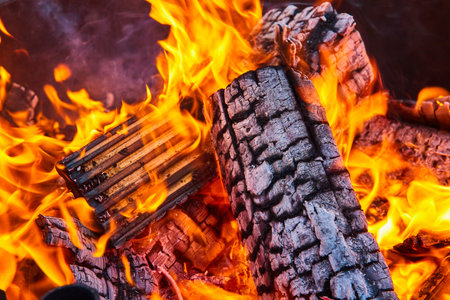Close up of destroyed wooden logs in fire with large yellow and orange flames background asset