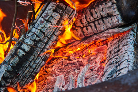 Ash covered logs with yellow and orange flames close up background assetの写真素材